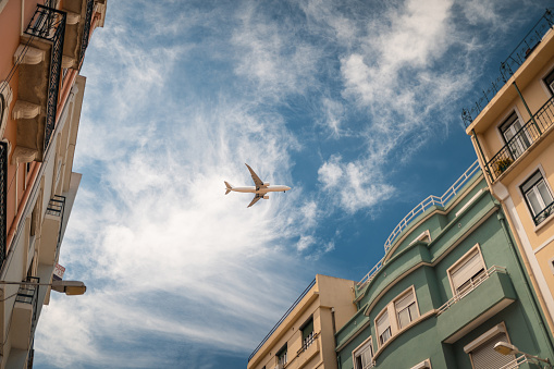 A distant airplane, aeroplane leaving a vapour trail from its four jet engines far up in a deep blue sky