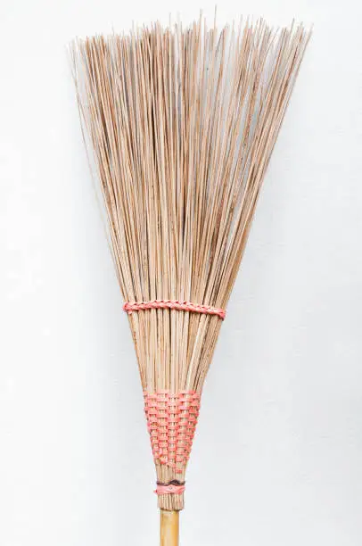 coconut broom stick leaning on the white wall,broom for cleaning on dirty floor, cleaning set in house or work place