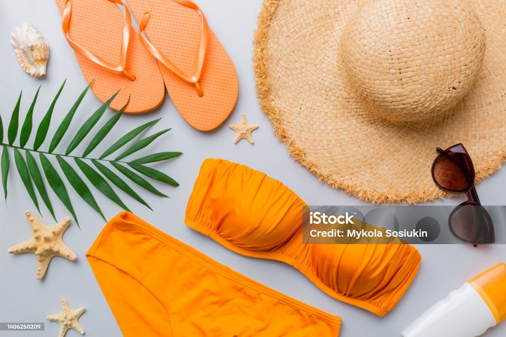 Woman swimwear and beach accessories flat lay top view on colored background Summer travel concept. bikini swimsuit, straw hat and seasheels. Copy space Top view Woman swimwear and beach accessories flat lay top view on colored background Summer travel concept. bikini swimsuit, straw hat and seasheels. Copy space Top view. Swimwear Stock Photo