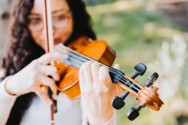 istock curly brunette woman doing pizzicato technique in violin. Selective focus. 1406252615