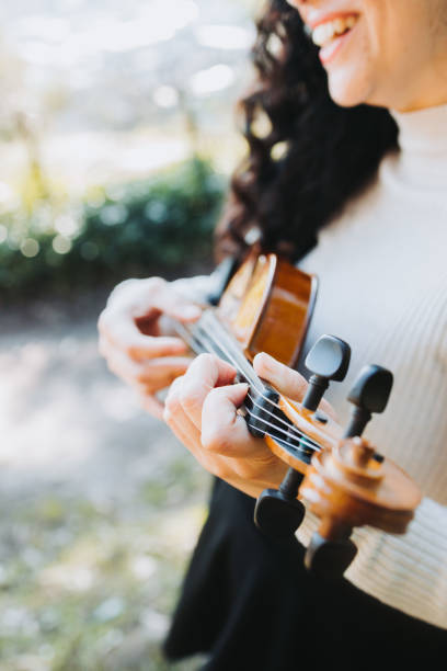 istock smiling curly brunette woman doing pizzicato technique in violin. Selective focus. 1406252656