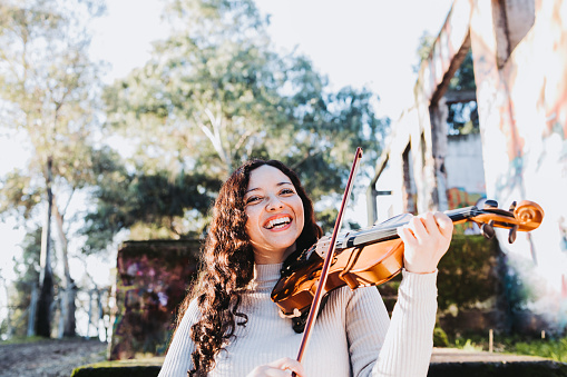 Smiling brunette woman playing violin and going down stairs.
