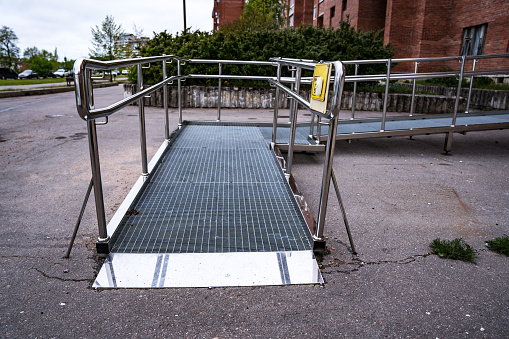 A ramp and a call button for people with disabilities near a public building. Iron ramp for the disabled at the entrance to the city library