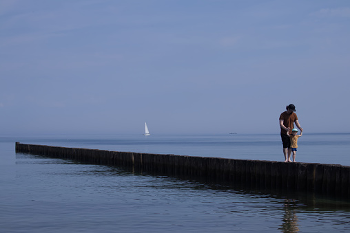 Dad and son walk on the breakwaters holding hands