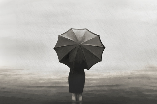 surreal lonely woman walks in the sea in the rain protected by an umbrella