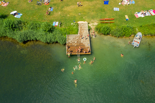 Aerial view of a beach at the lake with people swimming and sunbathing, holiday time.