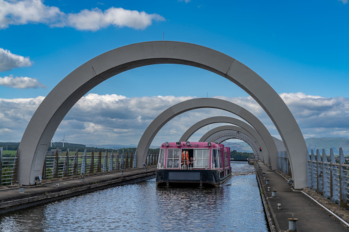Falkirk, United Kingdom - 19 June, 2022: view of a tourist boat cruise on the Union Canal after leaving. The Falkirk Wheel hydraulic boat lift