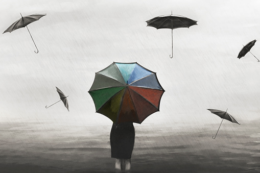 surreal woman with colorful umbrella in the rain with flying black umbrellas around