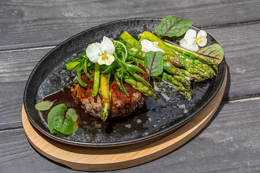 Hambagu (Hamburger Steak) with asparagus and green onion served on a cast iron pan. Image can be utilized editorially or commercially.