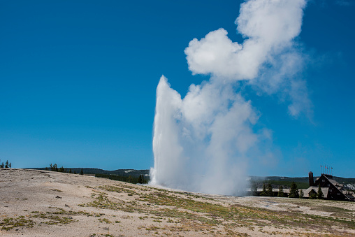 Old Faithful Geyser in the Upper Geyser Basin in Yellowstone National Park, Wyoming. An eruption with water and steam in the sky.