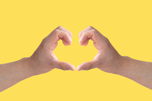 istock Two white hands making the shape of an open heart on a yellow background 1406271664