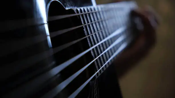 Photo of Close-up of man's hands playing on black acoustic guitar. Concept. Concept of music lessons