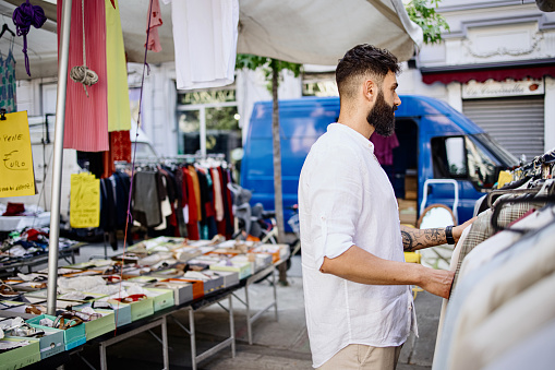 Male friends shopping in a second hand market in summer, zero waste concept