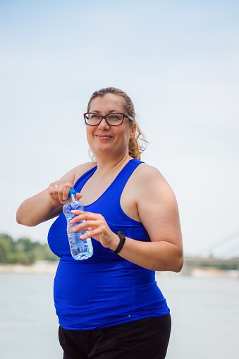 Happy woman taking a break from outdoor workout and having a bottle of water