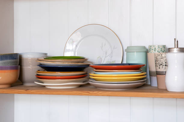 istock Wooden shelf with kitchen utensils, rustic style. Tableware, plates and cups stand on a shelf in the kitchen. Cupboard with set of colourful dishes, modern interior. 1406273761