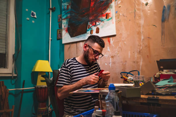 istock Guy with glasses in a studio chopping red paper. Craftbooking. Art 1406275924