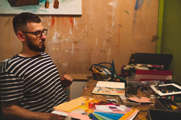istock Guy sitting in a studio and looking at his work. Craftbooking. Art. Pictures, paintings 1406275925