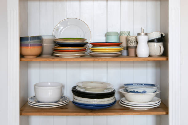 istock Wooden cabinet shelf with kitchen utensils, rustic style. Tableware, plates and cups stand on a shelf in the kitchen. Cupboard with set of colourful dishes, vintage style interior. 1406275926