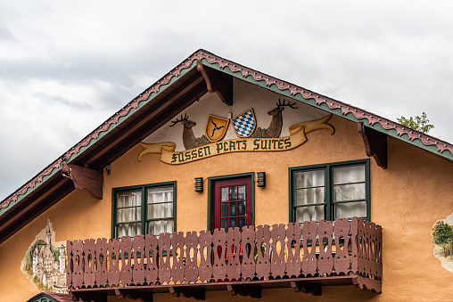 Helen, USA - October 5, 2021: Bavarian village of Helen, Georgia with closeup of balcony on traditional building with sign for Fossen Pcatz Suites hotel and cloudy sky