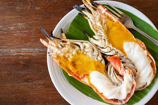 Close up view at one Grilled Giant River Prawn and fat shrimp serve on white plate on wooden table.