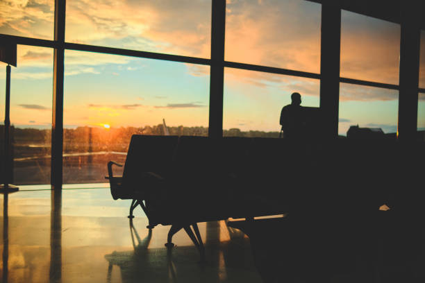 istock Empty chairs in airport departure hall with sunset view, blurred airplane in the background. 1406287247
