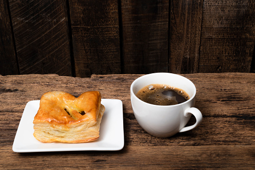 Espresso coffee and chicken pie in plate on isolated wood table background close up, top view, breakfast food and drink concept.