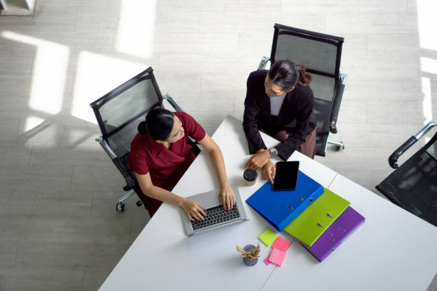 istock Two asian businesswoman meeting in modern office with laptop computer, tablet, document folder and coffee on table. People corporate business team concept. Top View 1406294884