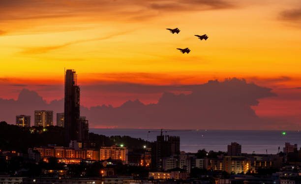 ビルの街並み美しいオレンジ色の夕焼けの空の背景を持つシルエットの飛行機。 - air force military us military armed forces ストックフォトと画像