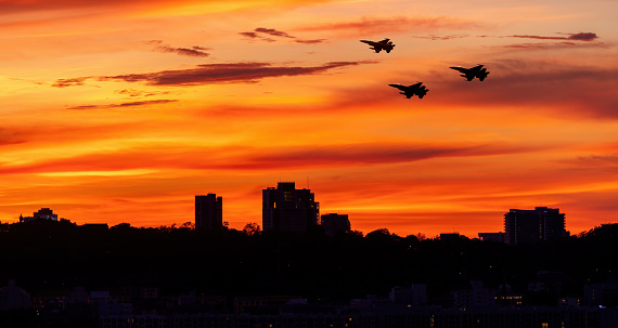 Silhouette airplane with building city scape beautiful orange sunset sky background.