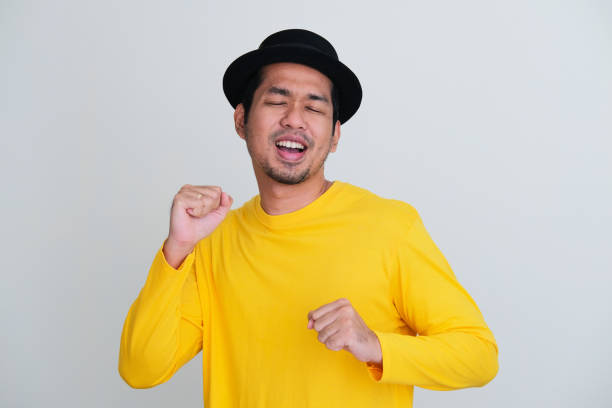 erwachsener asiatischer mann in gelber kleidung, der glücklich mit geschlossenen augen tanzt - menari stock-fotos und bilder