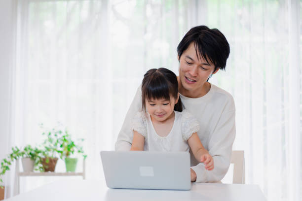 istock Little girl using the computer with her father 1406296774