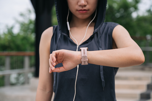 Unknown beautiful Asia woman checking smart watch after exercise jogging