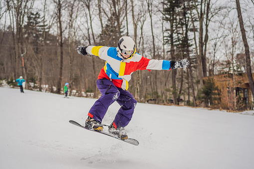 Young man jumping with a snowboard in the mountains.