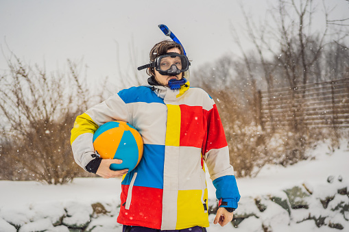 The man went outside in winter in snorkeling equipment and with a beach ball. A man dreams of a vacation at sea.