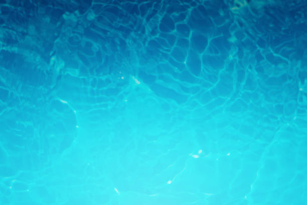Defocus blurred transparent blue colored clear calm water surface texture with splashes and bubbles. Trendy abstract nature background. Water waves in sunlight. blue water background.