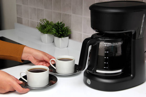 Woman's hands serve coffee prepared in a coffee maker to start the day with the benefits of antioxidants, protects against cancer, fights Alzheimer's and Parkinson's Woman's hands serve coffee prepared in a coffee maker to start the day with the benefits of antioxidants coffee maker stock pictures, royalty-free photos & images
