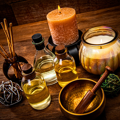 This is a photograph taken in the studio of essential oils and a singing bowl on a wood background