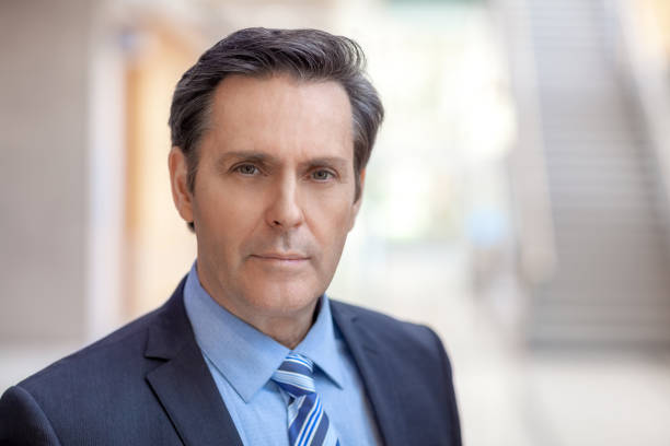 Headshot portrait of mature real estate agent businessman standing in office hall lobby stock photo