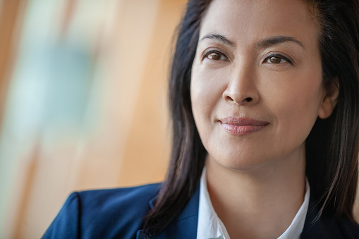 Headshot portrait of Chinese businesswoman looking away at office