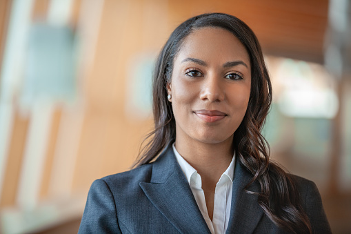 Portrait of multiracial African American Black young businesswoman standing in office lobby smiling at camera