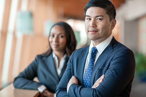 Portrait of Pacific Islander mid adult businessman with multiracial female Black coworker in office