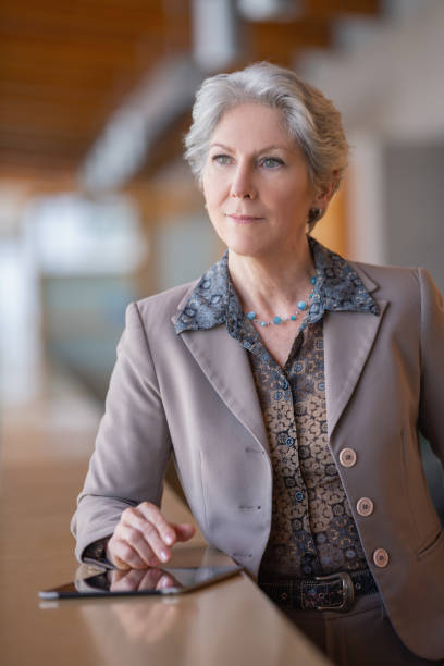 istock Senior woman creative designer checking e-mail with digital tablet looking away portrait 1406309054