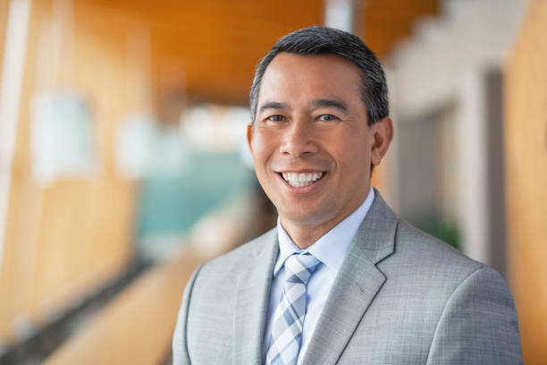 Portrait of mature multiracial Asian businessman in office lobby smiling stock photo