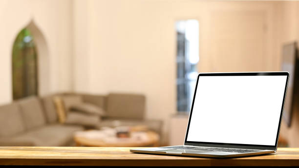 istock Laptop computer on wooden table against blurred modern living room in background. Empty display for your advertise text. 1406310350