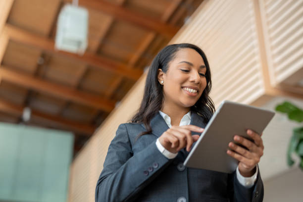 Portrait of multiracial African American Black businesswoman using internet with digital tablet low angle view Portrait of multiracial African American Black businesswoman using internet with digital tablet low angle view women satisfaction decisions cheerful stock pictures, royalty-free photos & images