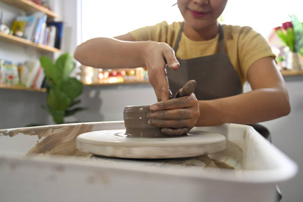 istock Woman in apron creating handicraft crockery on the pottery wheel in workshop. Activity, handicraft, hobbies concept. 1406310464