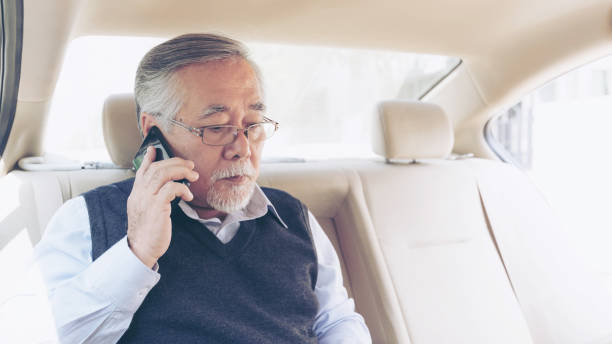 istock Business senior rich man Stock trader player in suit working with laptop computer and using a smart phone in his car , concept for senior business success 1406312272