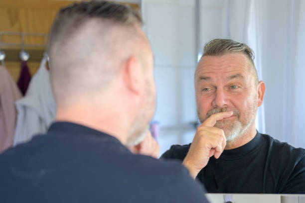 istock Senior man looking at his reflection with a rueful smile 1406313453