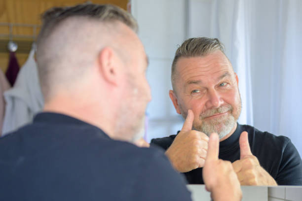 istock Smiling satisfied man looking at himself in the mirror 1406313454