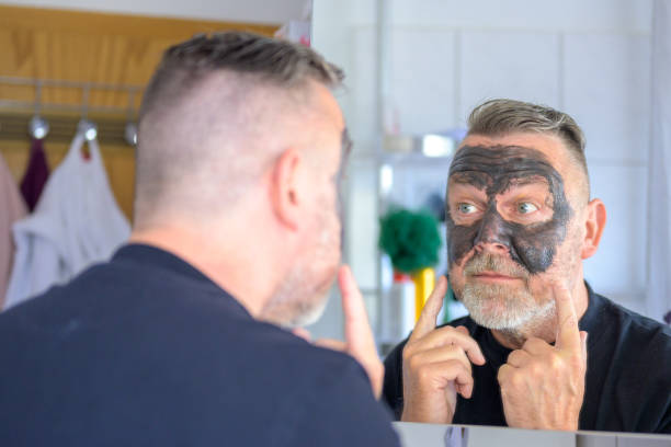 bärtiger mann mittleren alters mit kosmetischer gesichtsmaske - airport check in counter stock-fotos und bilder